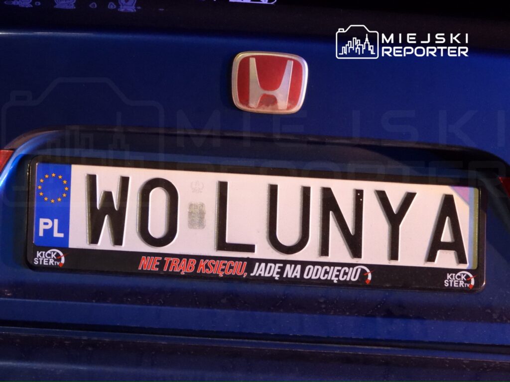 Rejestracja samochodu z napisem "WO LUNYA" oraz hasłem "NIE TRĄB KSIĘCIU, JADĘ NA ODCIĘCIU" na niebieskim tle.