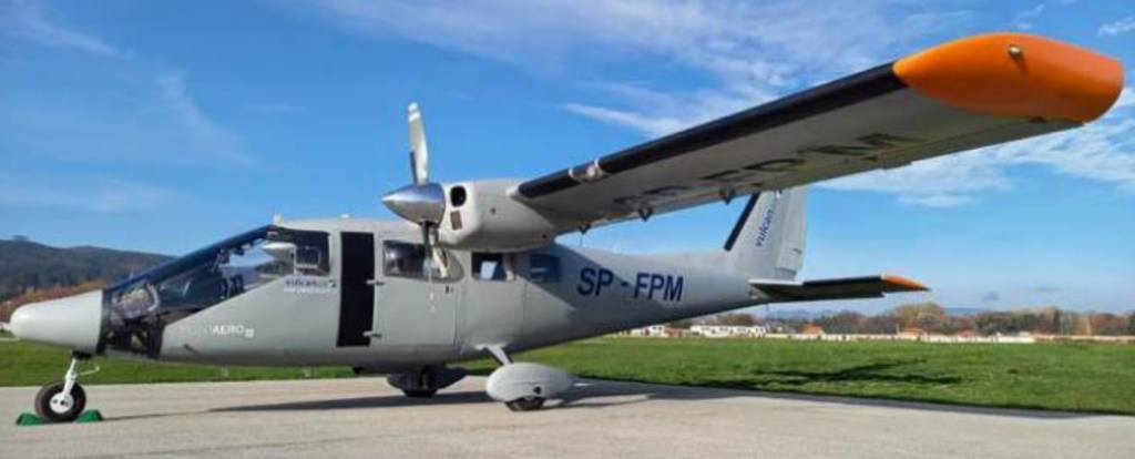 Samolot z oznaczeniem SP-FPM stoi na pasie startowym, na tle błękitnego nieba i zielonej trawy.