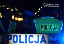 Policjanci w odblaskowych kamizelkach kontrolują sytuację nocą przy oświetlonych ulicach.
