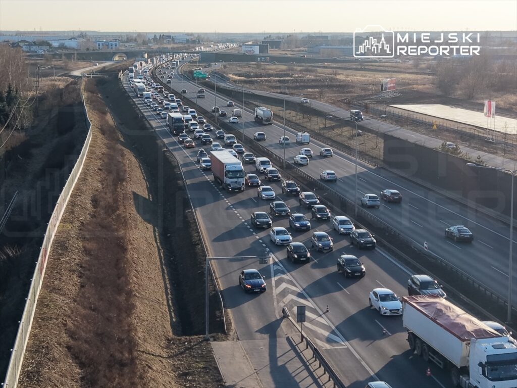Korek drogowy z dużą liczbą samochodów osobowych i ciężarówek na autostradzie w słoneczny dzień.