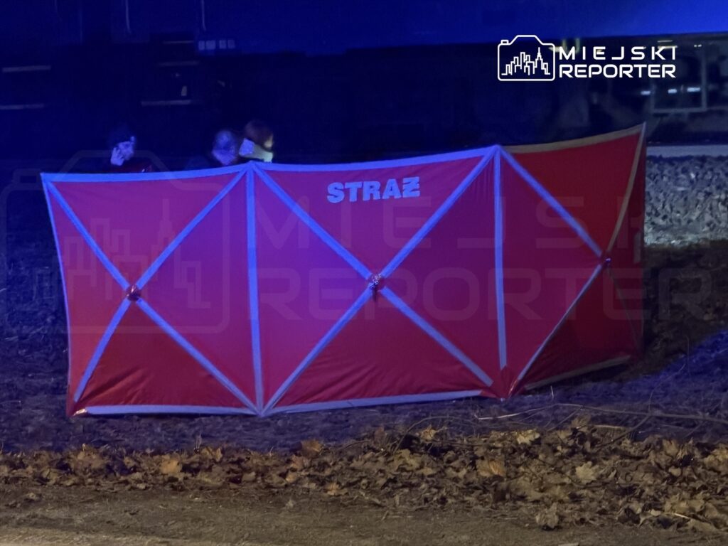 Czerwony namiot ratunkowy z napisem "STRAŻ" ustawiony w terenie z widocznymi osobami w tle.