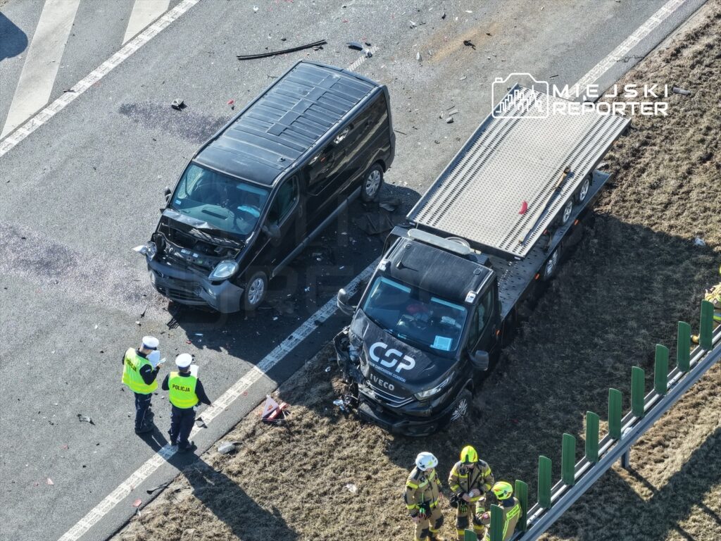 Dwa pojazdy po wypadku drogowym, policjanci i strażacy pracują na miejscu zdarzenia.