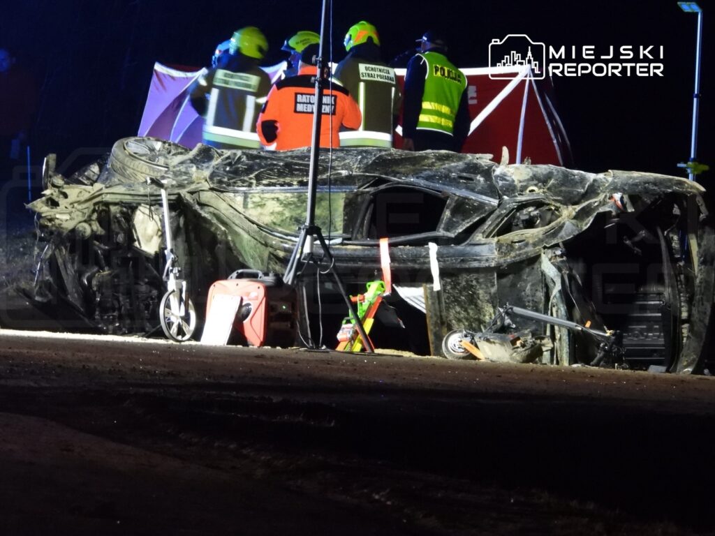 W nocy zespół ratunkowy prowadzi działania przy przewróconym samochodzie osobowym na drodze.