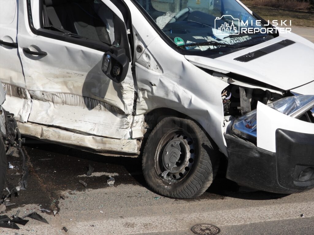 Zniszczony dostawczy samochód na drodze, z uszkodzoną przednią częścią i wgniecionymi drzwiami.