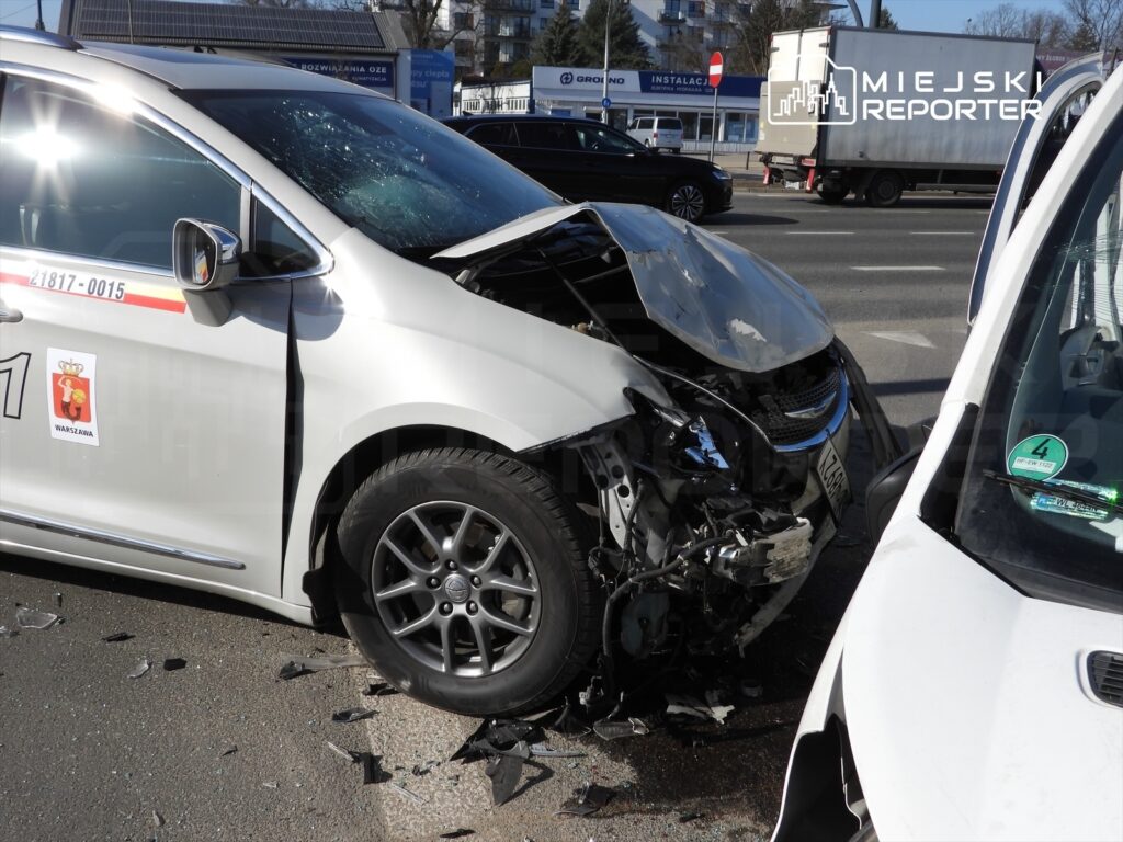 Zderzenie dwóch samochodów osobowych na miejskiej ulicy, jeden z pojazdów ma poważnie uszkodzoną przednią część.