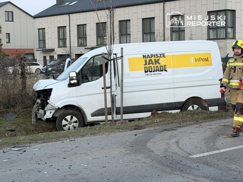 Uszkodzony samochód dostawczy InPost stoi na poboczu drogi, obok niego strażak z narzędziami.
