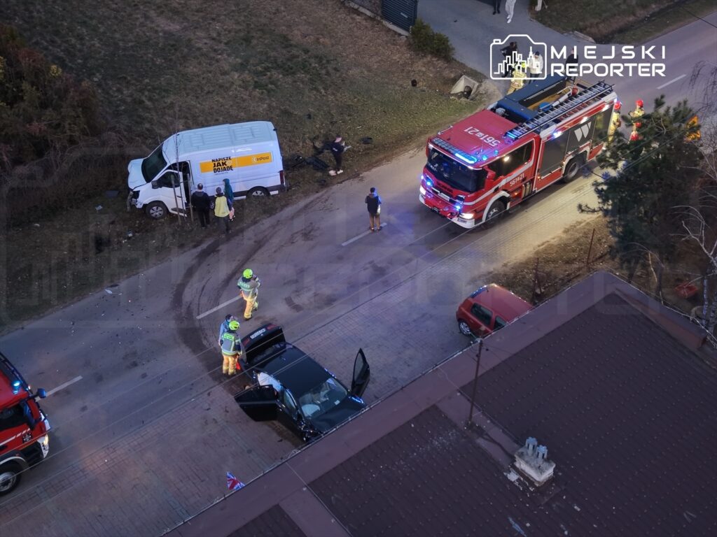 W pobliżu drogi, strażacy badają wypadek dwóch pojazdów, w tym czarnego samochodu osobowego i dostawczego.