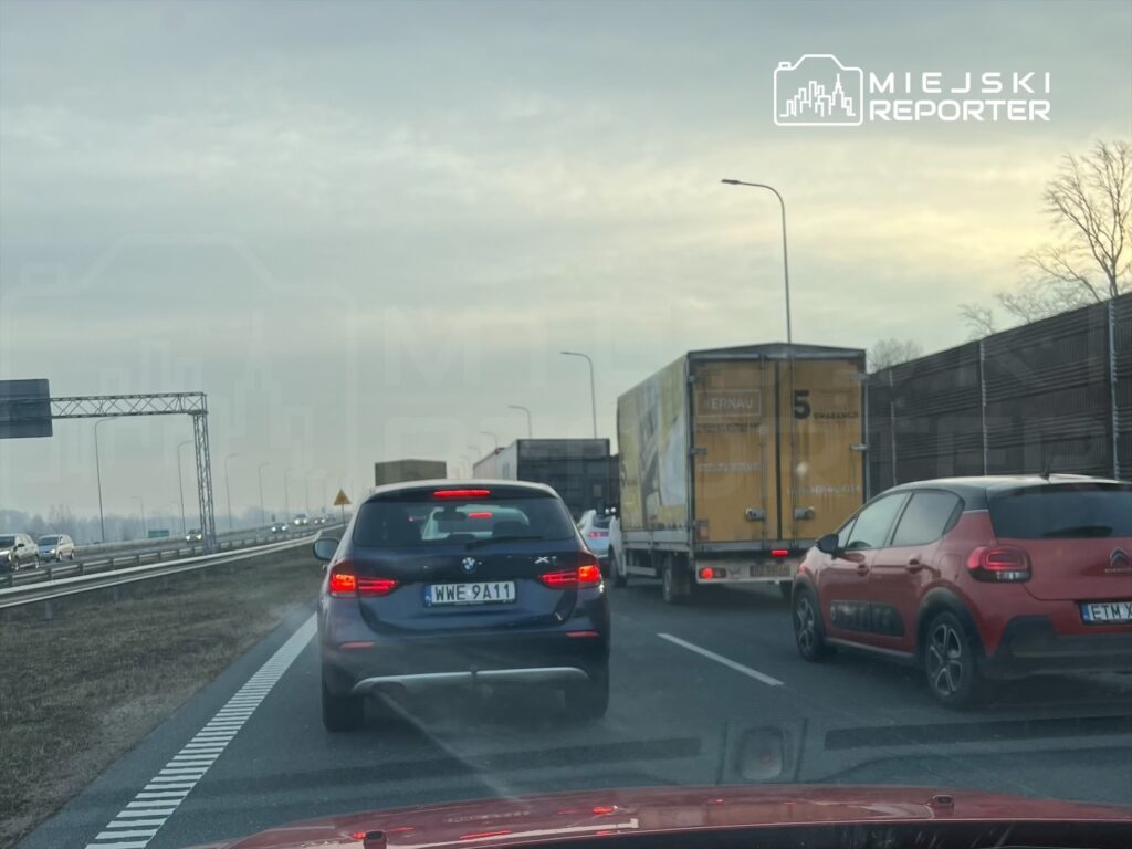 Zatory drogowe na autostradzie, samochody osobowe i ciężarowe stoją w korku w pochmurny dzień.