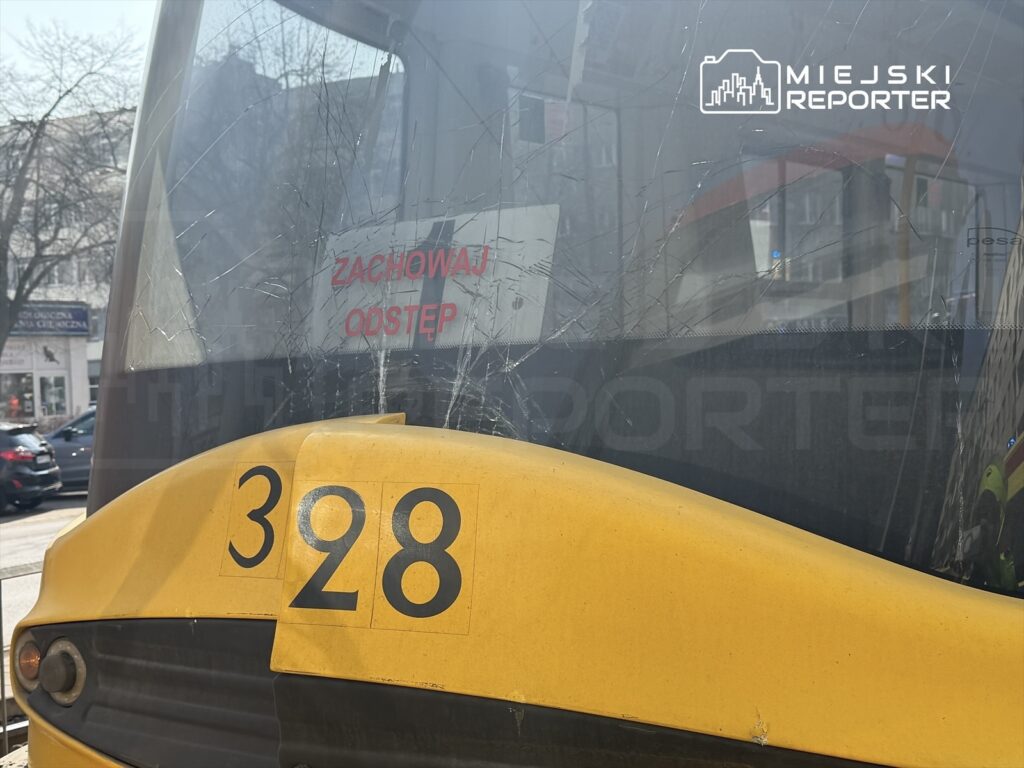 Żółty tramwaj z numerem 328 zatrzymany na przystanku, z widocznym napisem „ZACHOWAJ ODSTEP” na szybie.