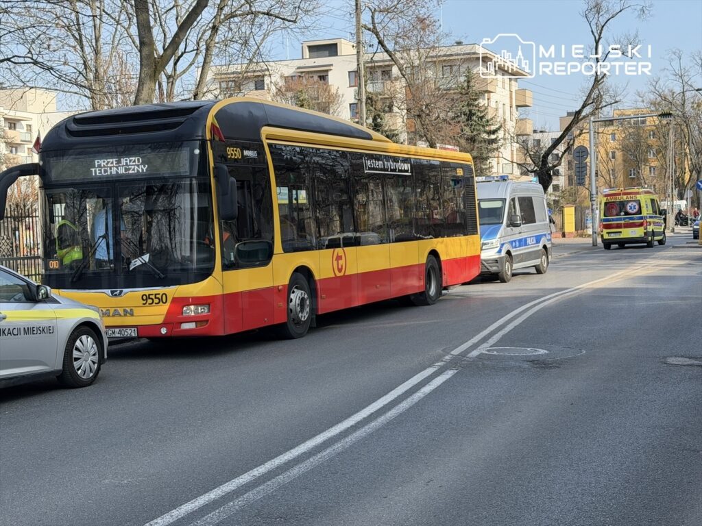 Autobus komunikacji miejskiej zatrzymany na ulicy, obok policyjny radiowóz oraz ambulans. Na wyświetlaczu autobusu napis „PRZEJAZD TECHNICZNY”.