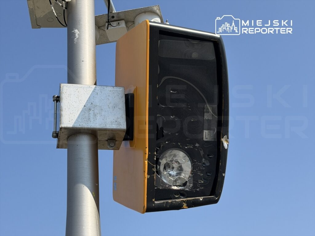 Lampa sygnalizacyjna zamontowana na metalowym słupie, na tle błękitnego nieba.