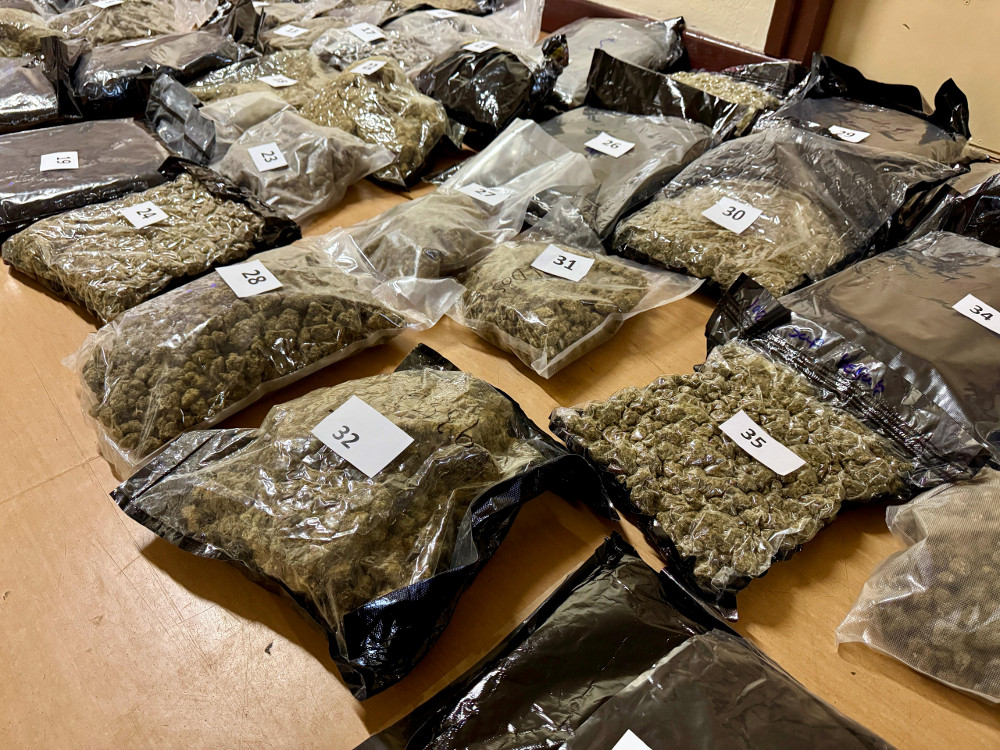 Pakiety z suszem roślinnym ułożone na podłodze, oznaczone numerami, w pomieszczeniu o neutralnym wystroju.