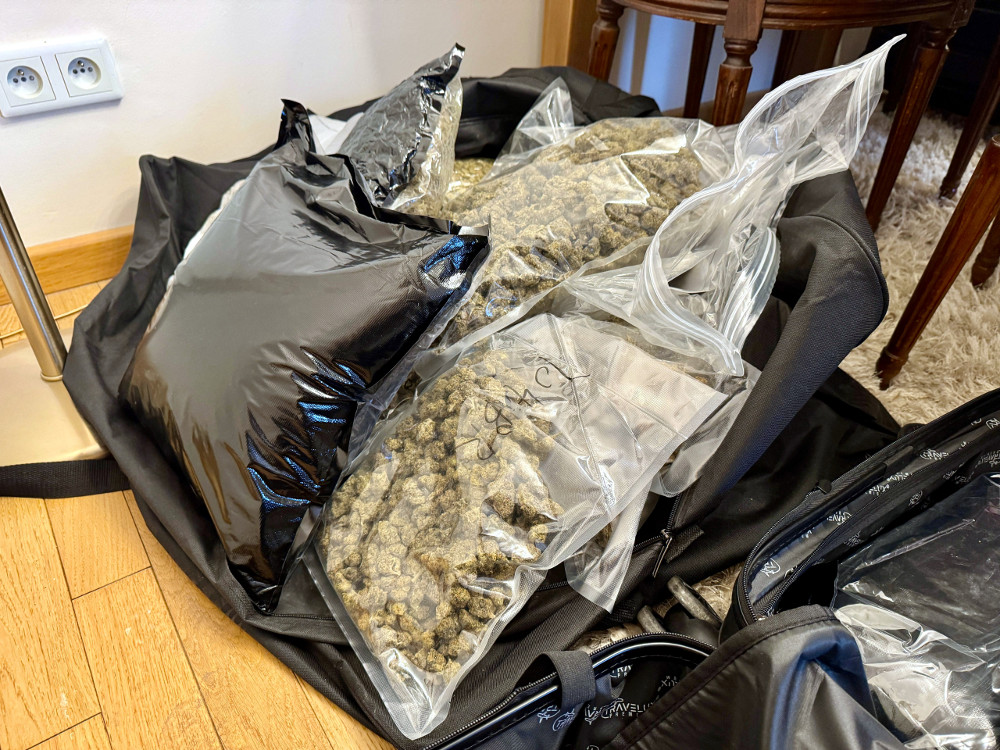 W torbie leżą przezroczyste worki z suszem roślinnym obok czarnych pakunków, na drewnianej podłodze.