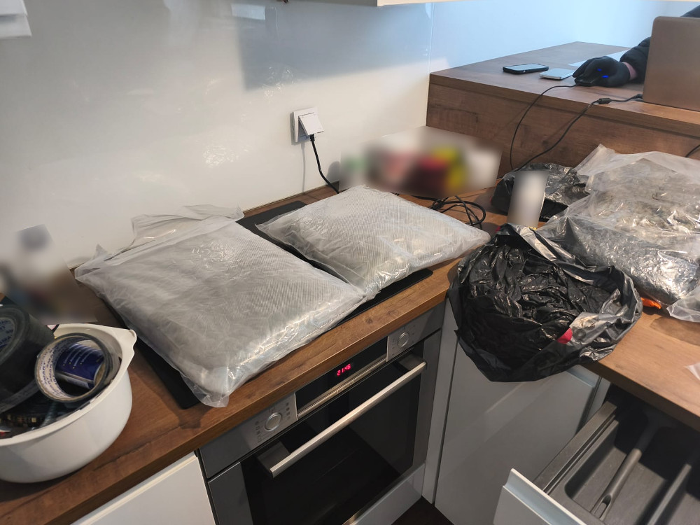 Na blacie kuchennym znajdują się dwa pakunki w folii, obok czarna torba i zestaw narzędzi.