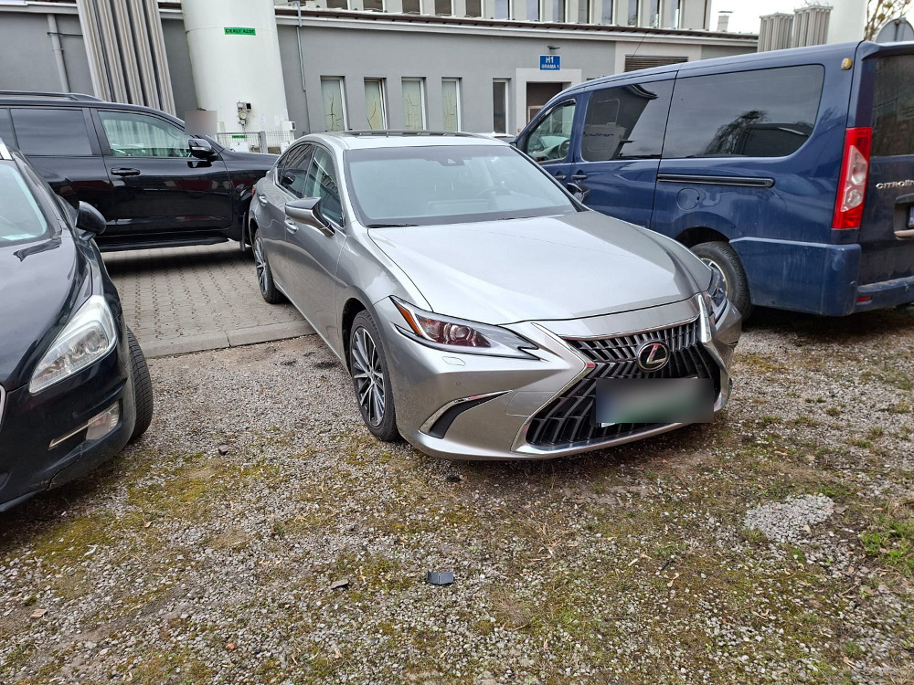 Luksusowy samochód osobowy marki Lexus zaparkowany na podjeździe w otoczeniu innych pojazdów.