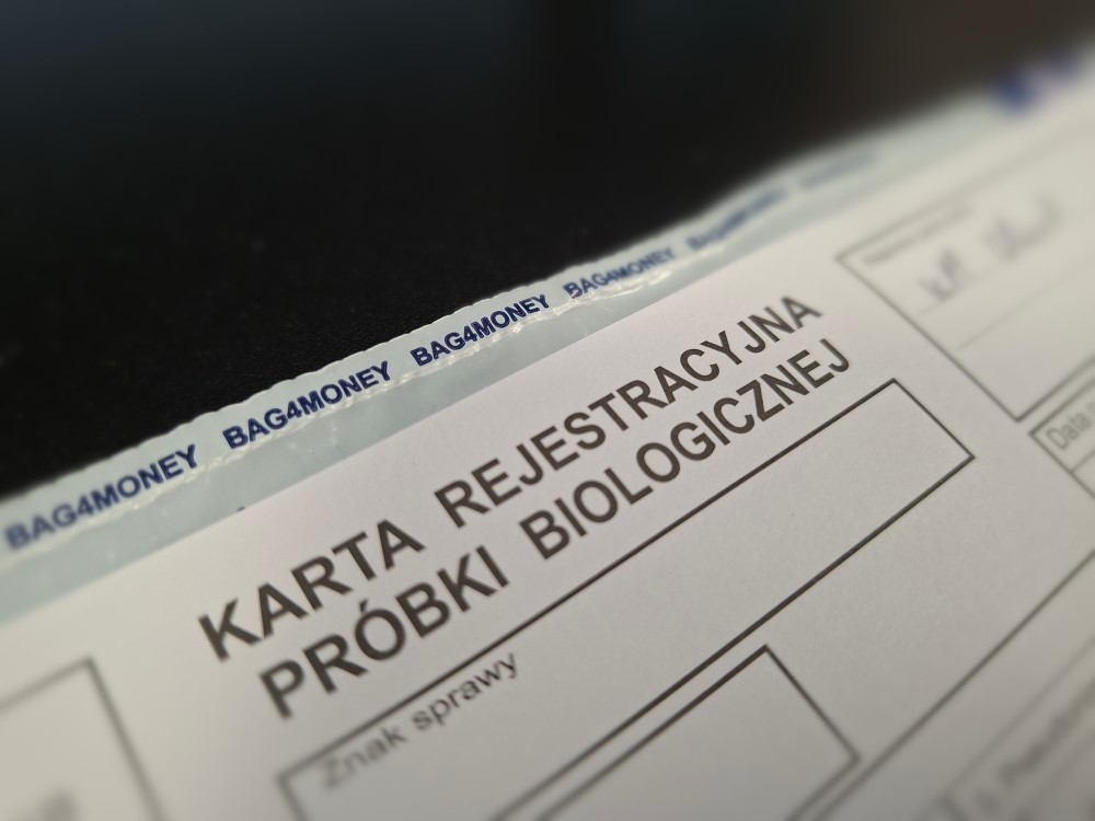 Karta rejestracyjna próbki biologicznej leżąca na czarnym tle z widocznym napisem "KARTA REJESTRACYJNA PRÓBKI BIOLOGICZNEJ".
