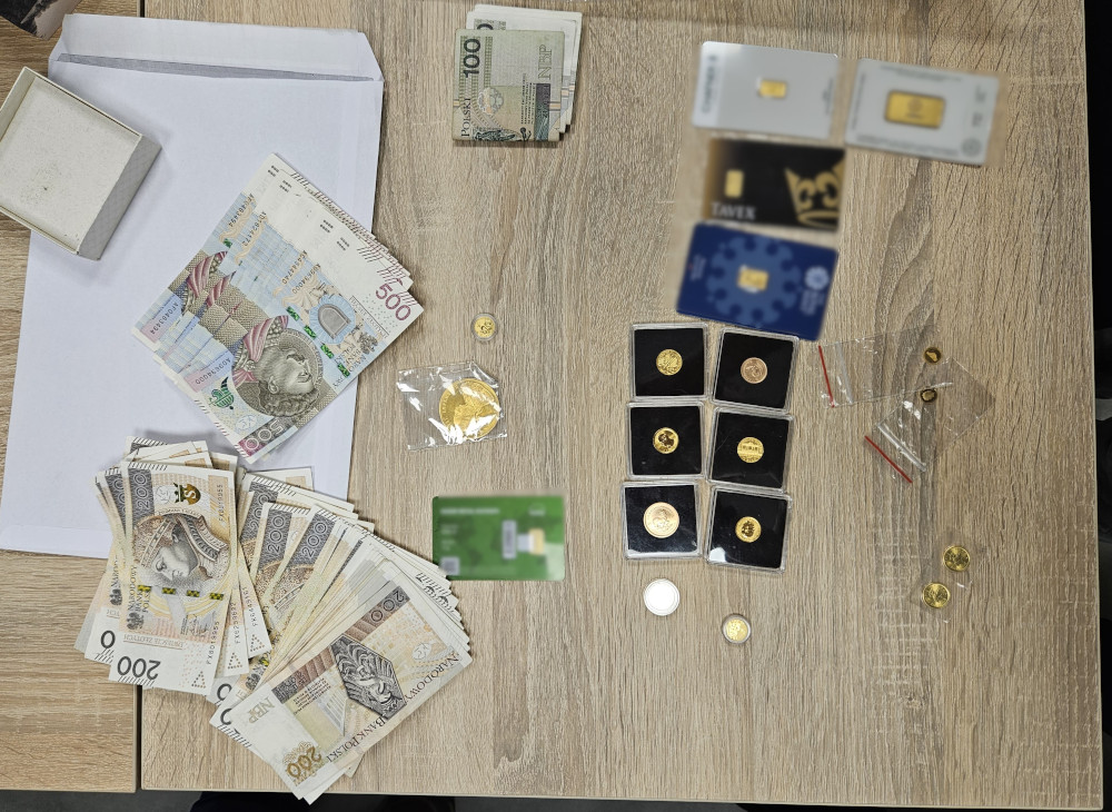 Stos pieniężny, złote monety oraz karty SIM ułożone na drewnianym stole.