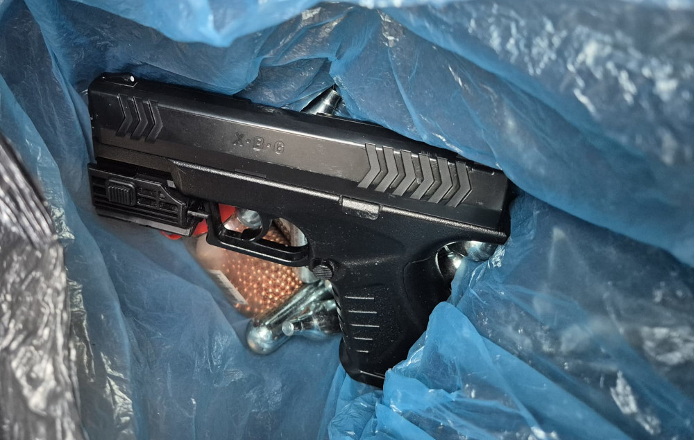 Pistolet leżący w niebieskiej torbie, obok metalowe elementy i kulki.