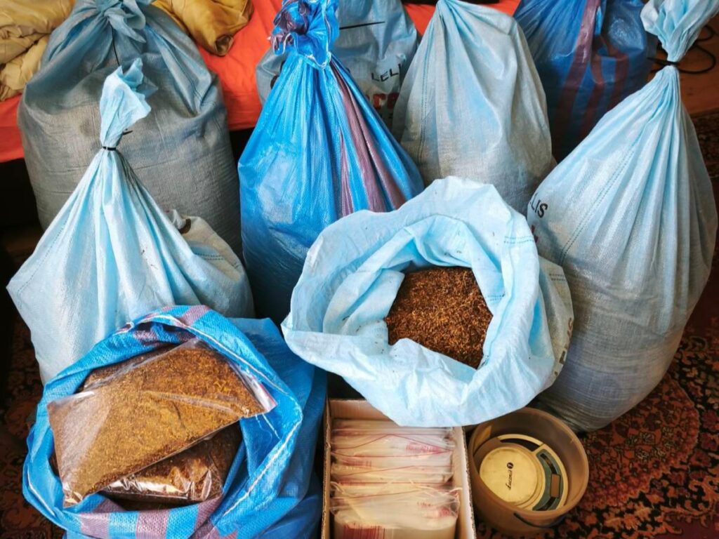 Sześć niebieskich worków z suszem, w tym jeden z otwartą górą, leży na dywanie obok pudełka z foliowymi torebkami.