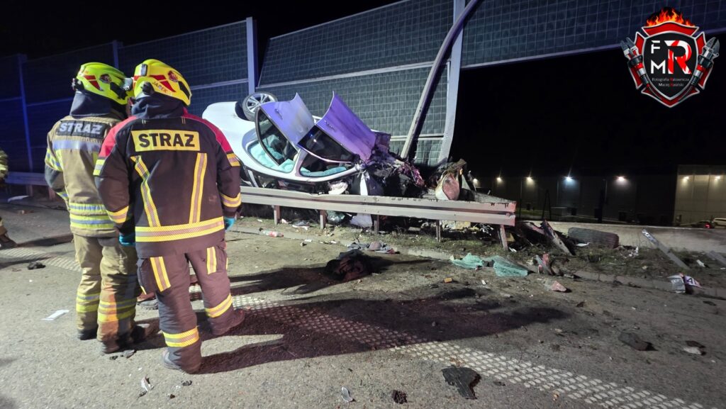 Strażacy w specjalistycznych ubraniach oceniają skutki wypadku samochodowego obok uszkodzonego pojazdu na autostradzie.