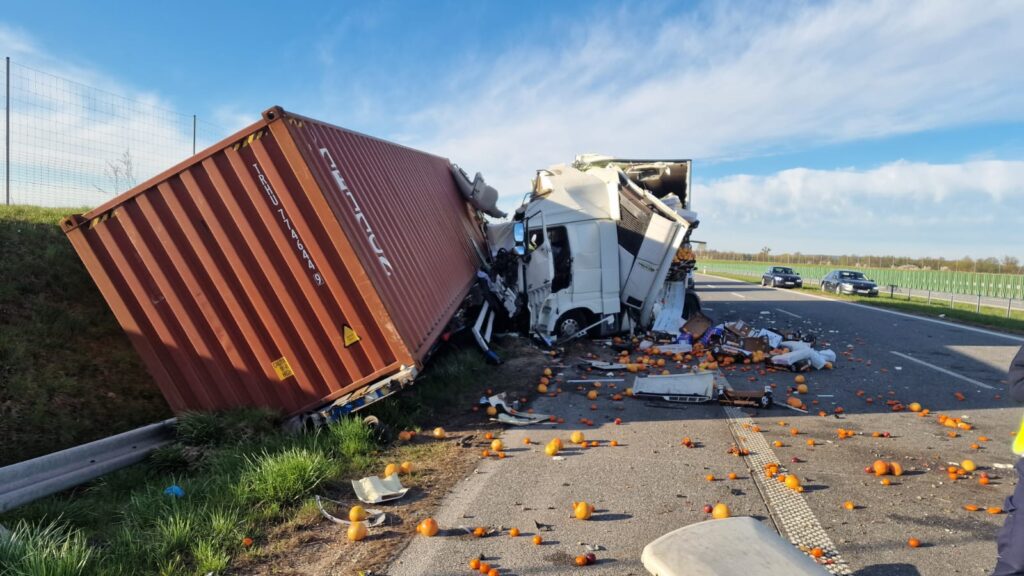 Wielka ciężarówka przewożąca pomarańcze wypadła z drogi, przewracając się na bok, a owoce rozsypały się na jezdni.
