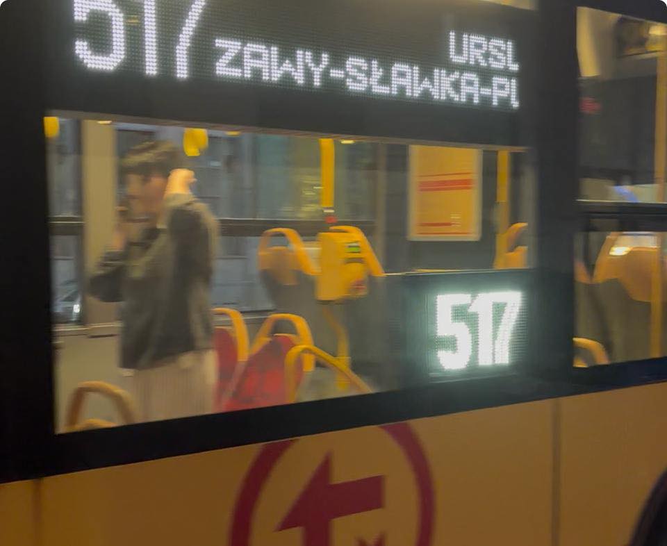 Mężczyzna rozmawiający przez telefon w tramwaju linii 517, z widocznymi pustymi siedzeniami.