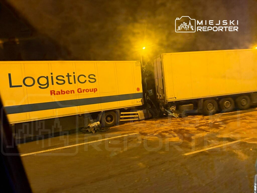 Dwa ciężarówki z logo "Logistics Raben Group" zderzone na drodze, w otoczeniu nocnego oświetlenia.