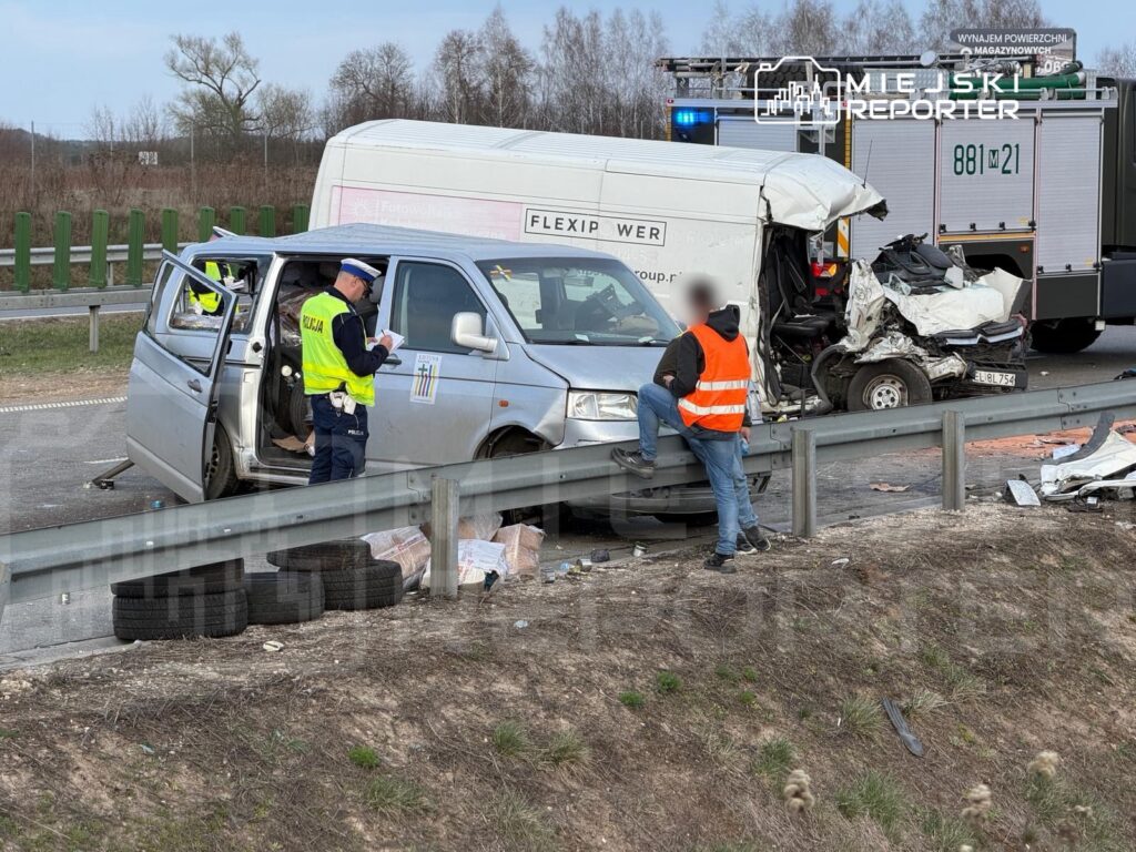 Policjant w kamizelce odblaskowej spisuje notatki obok uszkodzonego samochodu dostawczego na poboczu drogi.