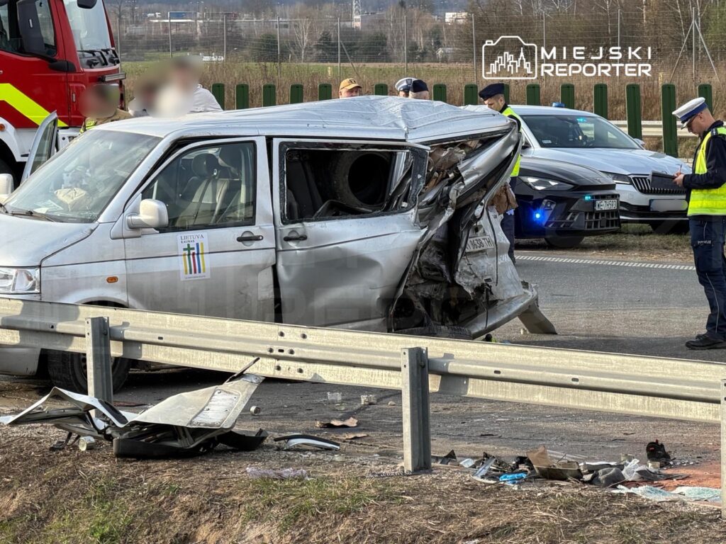 Rozbity samochód dostawczy z uszkodzoną tylną częścią stoi przy drodze, obok grupy funkcjonariuszy policji.