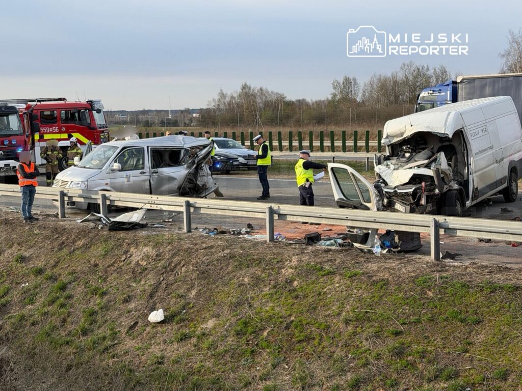 W wyniku wypadku drogowego na autostradzie uszkodzone są dwa pojazdy – osobowy i dostawczy. Ratownicy oraz policja pracują na miejscu zdarzenia.