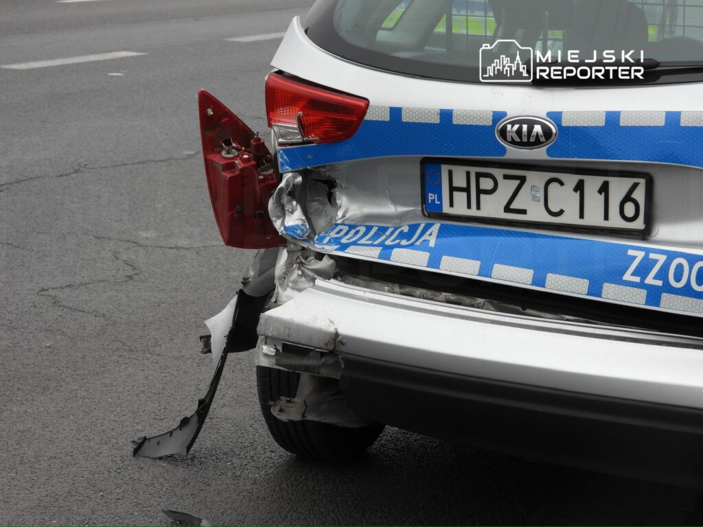 Uszkodzony tył radiowozu policyjnego z widocznymi wgnieceniami i zarysowaniami na drodze.