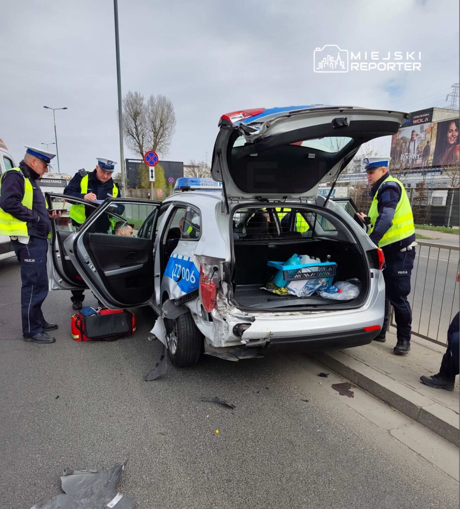 Policjanci zabezpieczają miejsce wypadku drogowego, gdzie uszkodzone auto stoi na jezdni.