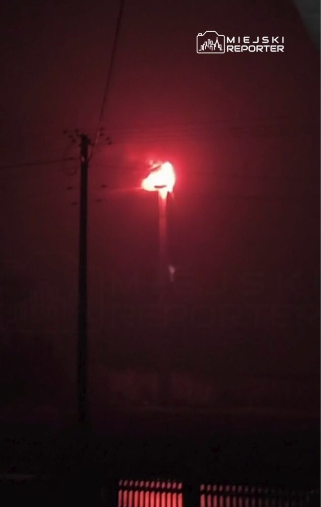 Czerwony płomień wydobywający się z latarni ulicznej w gęstej mgle nocnej.