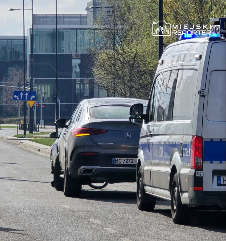 Mercedes GLE 350 d zatrzymany obok radiowozu policyjnego na ulicy w otoczeniu nowoczesnych budynków.