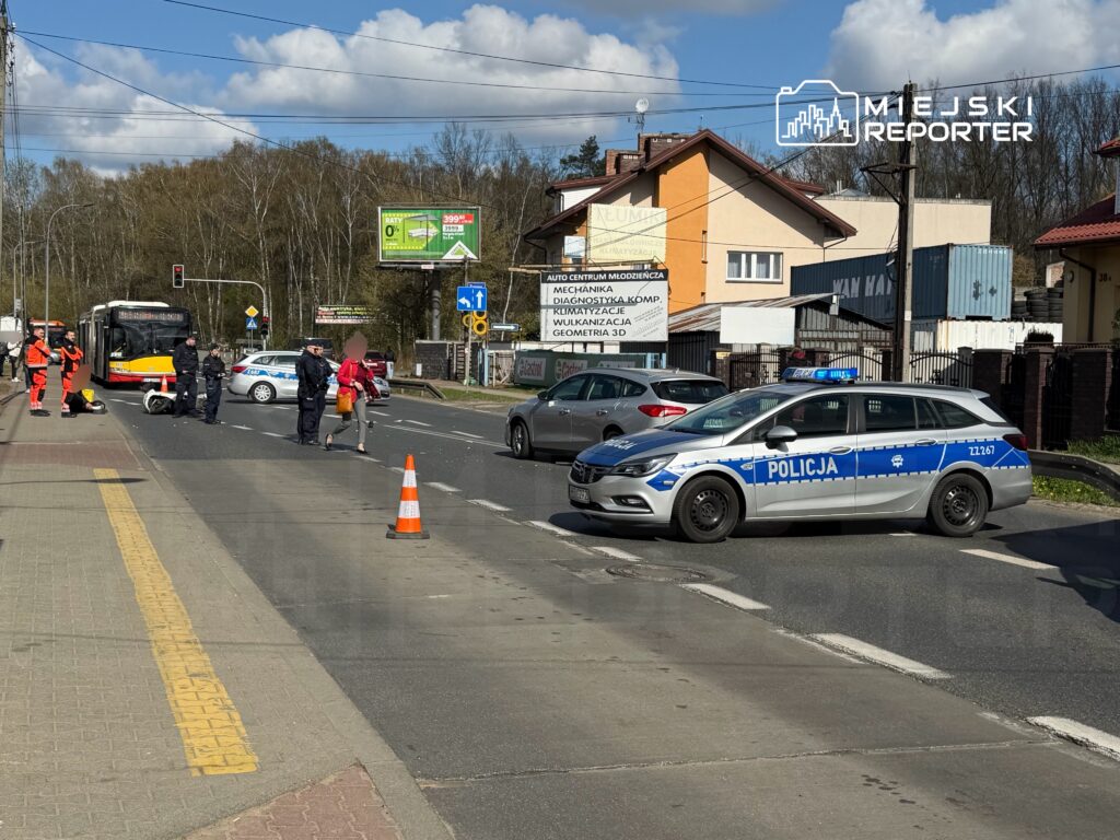 Na jezdni zatrzymany autobus, a obok niego interweniujący policjanci i ratownicy medyczni.