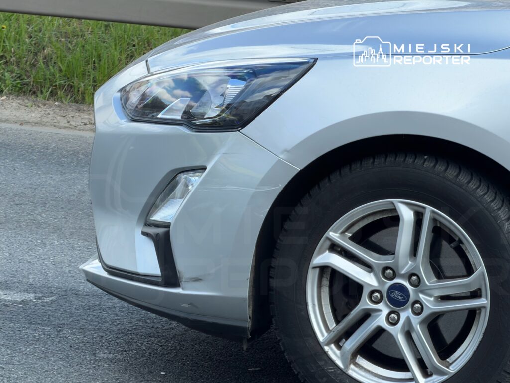 Srebrny samochód osobowy marki Ford zaparkowany na drodze, widoczny z boku, z wyraźnymi detalami felgi.