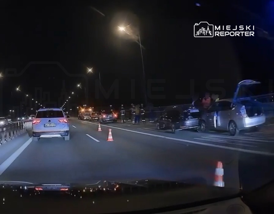 Na autostradzie w nocy, zablokowany pas ruchu, w tle widać kilka wozów strażackich i ludzi w mundurach.