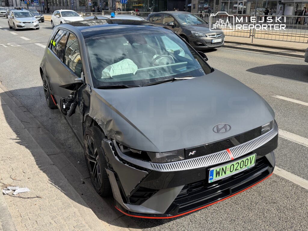 Uszkodzony samochód osobowy marki Hyundai stoi na ulicy, z widocznymi wgnieceniami na przednich drzwiach.