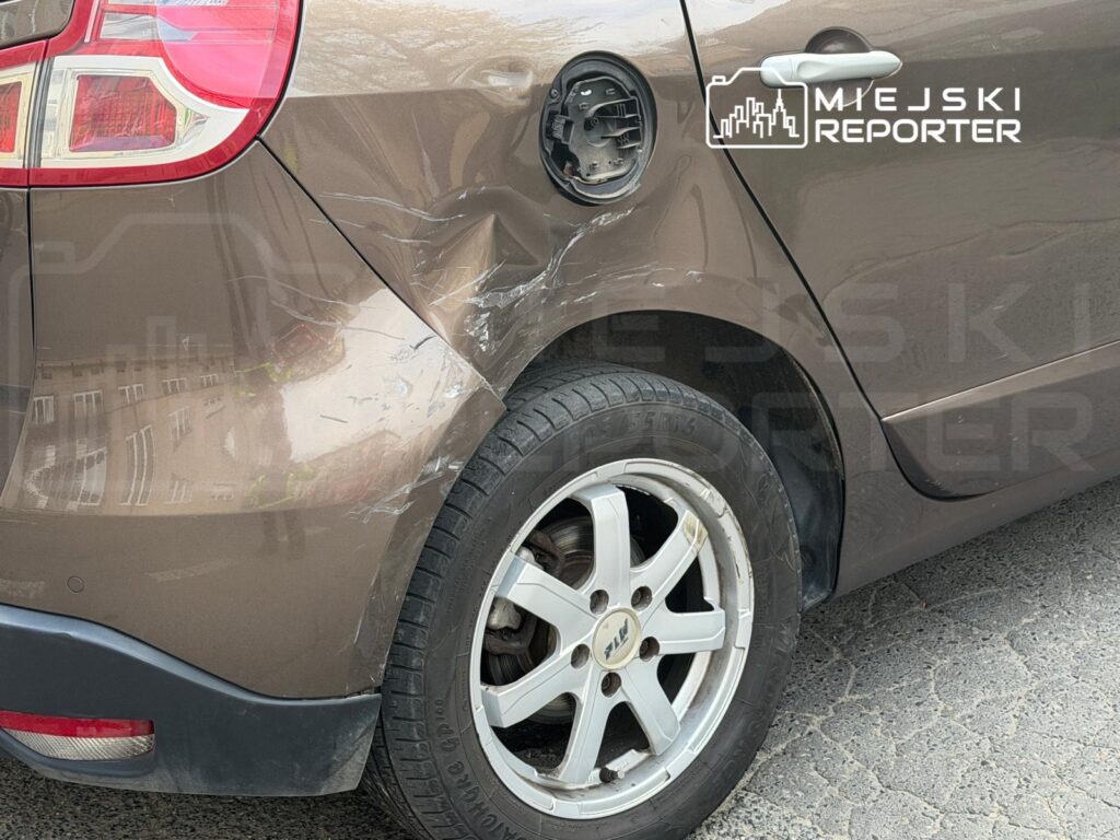 Uszkodzona tylna część brązowego samochodu osobowego z wgnieceniem i zarysowaniami na karoserii.