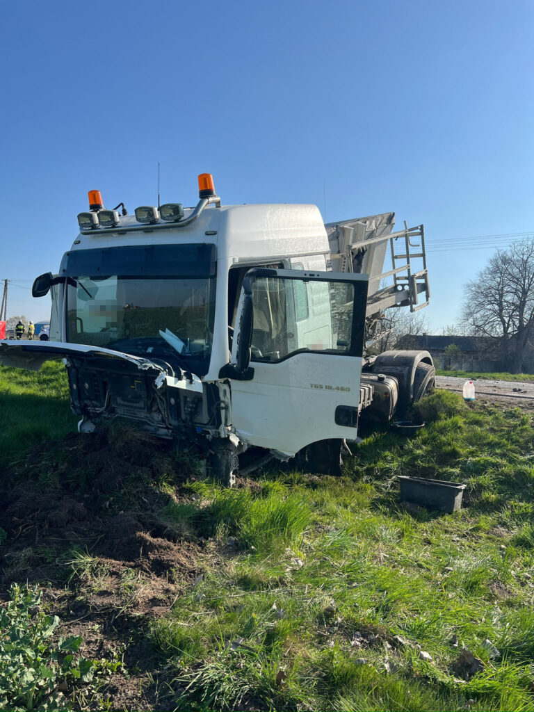 Uszkodzony samochód ciężarowy stoi na poboczu drogi, otoczony wysoką trawą w słoneczny dzień.