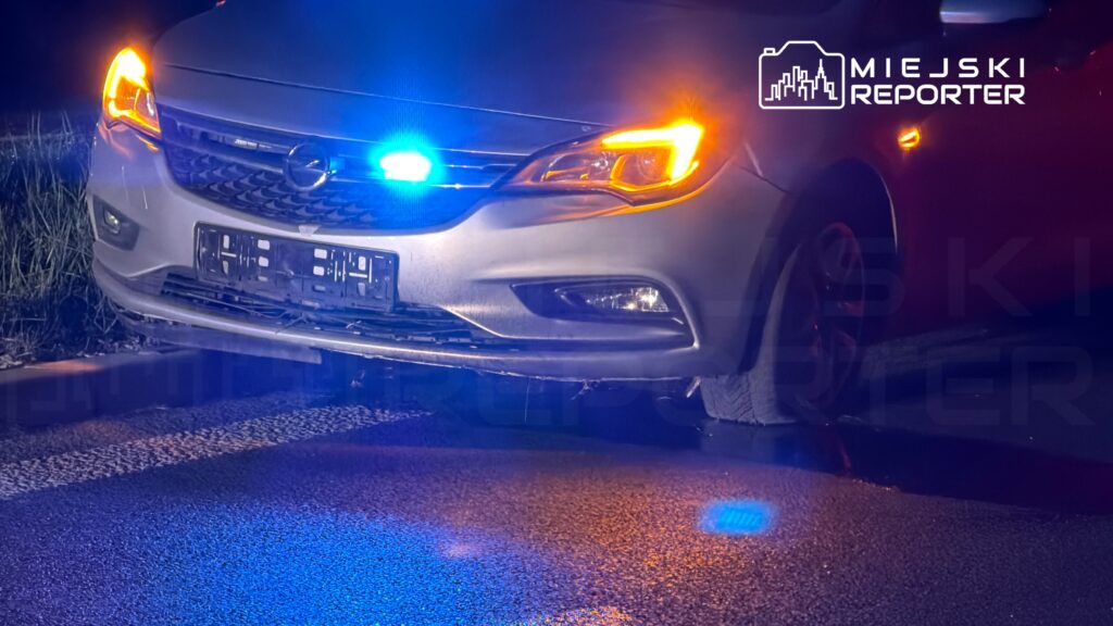 Policyjny samochód z niebieskimi i pomarańczowymi światłami sygnalizacyjnymi zatrzymany na drodze.