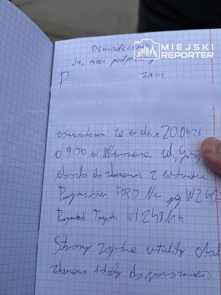 Osoba trzymająca otwartą, niebieską zeszytową książkę z odręcznym tekstem, zawierającym oświadczenie i dane dotyczące zdarzenia drogowego.