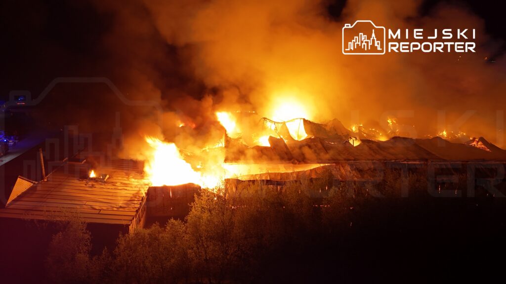 Intensywny pożar z płomieniami i dymem wydobywającymi się z zniszczonego budynku w nocy.