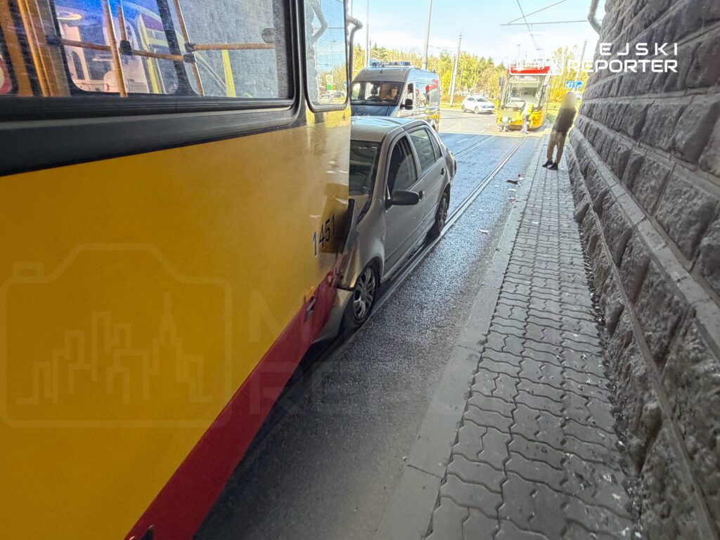 Złoty autobus komunikacji miejskiej zderzył się z szarym samochodem osobowym na wąskiej ulicy.