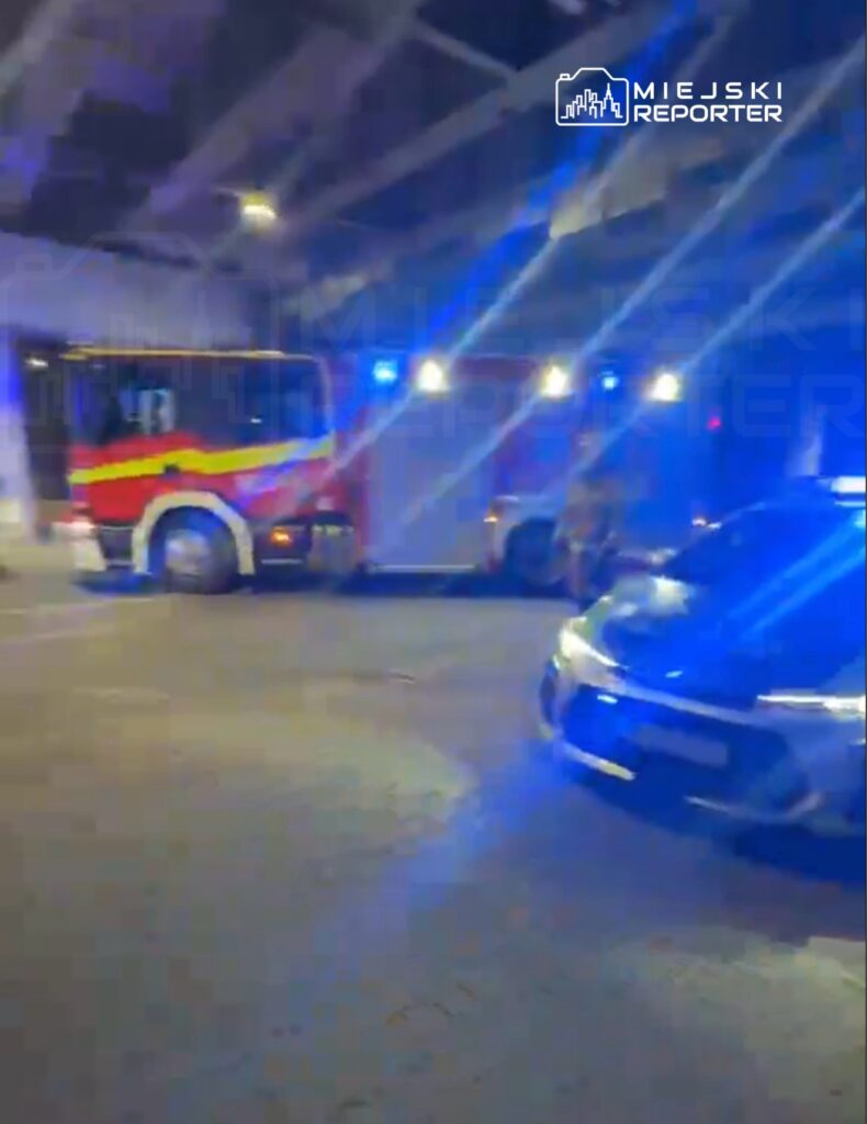 Straż pożarna z włączonymi sygnałami świetlnymi wjeżdża do podziemnego garażu.