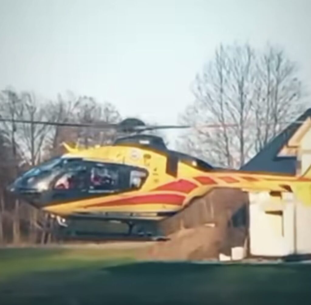 Śmigłowiec ratunkowy w żółto-czerwonym malowaniu startujący z terenu przydomowego.