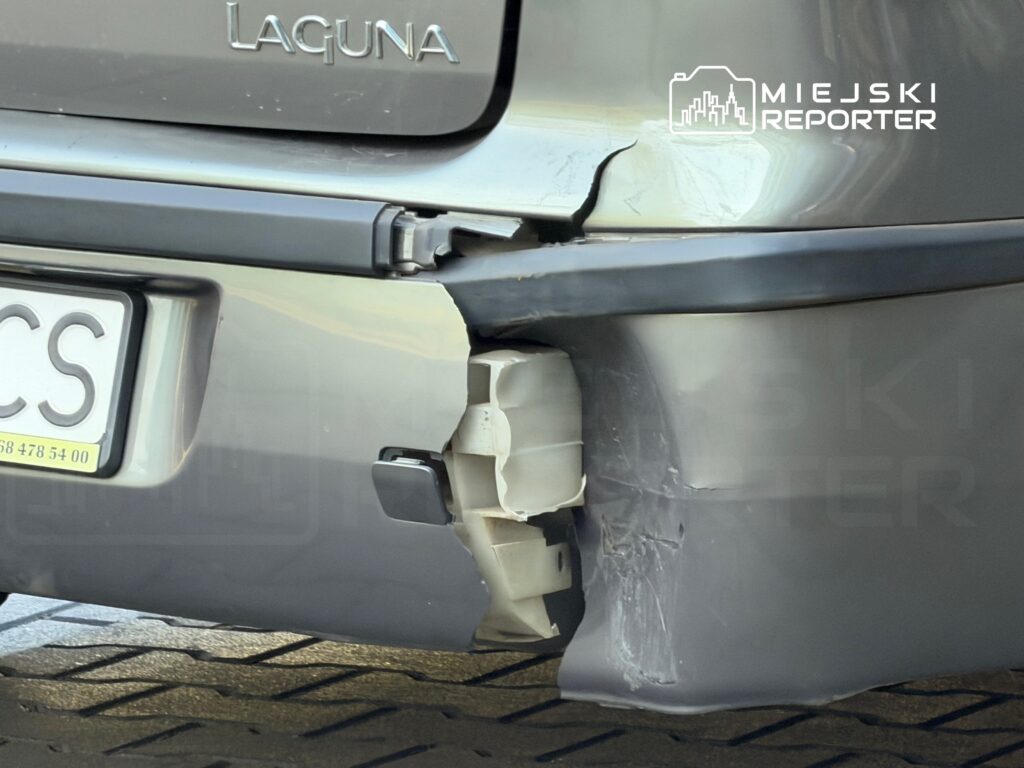 Uszkodzony tył samochodu marki Laguna z widocznymi zarysowaniami i odłamanym elementem zderzaka.