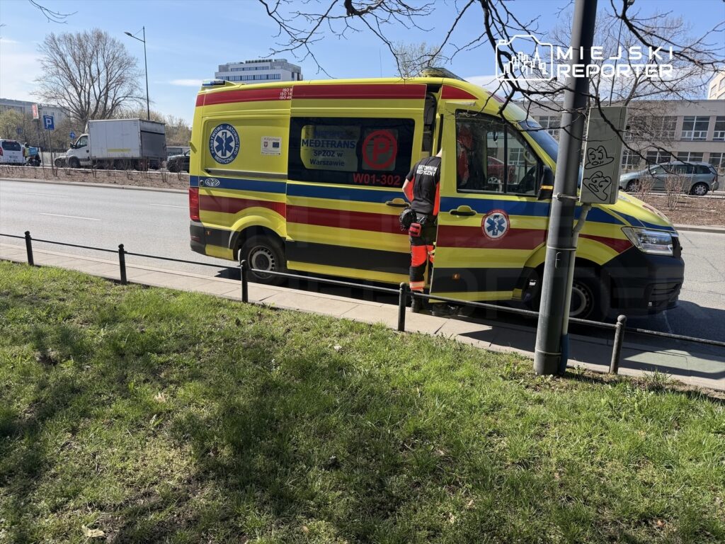 Zespół ratowników medycznych wchodzi do karetki pogotowia stojącej przy ruchliwej ulicy.