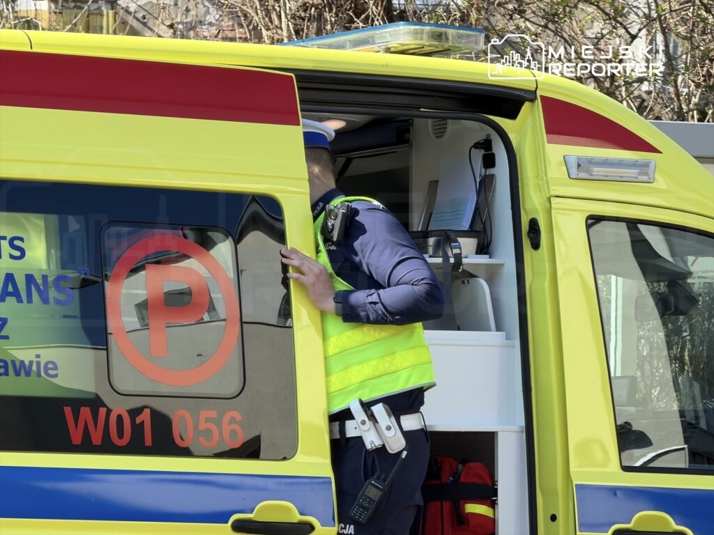 Mężczyzna w kamizelce odblaskowej wchodzi do otwartego pojazdu ratunkowego.