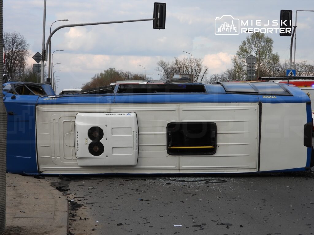 Przewoźnik leży na boku na drodze, otoczony fragmentami szkła i uszkodzonymi elementami.